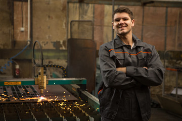 Industrial worker operating plasma cutter at the metal factory
