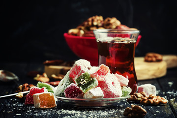 Black tea and candy with nuts on a dark background, selective focus