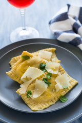 Homemade ravioli with spinach and ricotta cheese with grated parmesan on blue plate. Selective focus