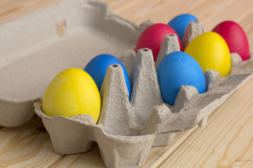Easter eggs in paper tray. Colorful eggs. Wooden background.