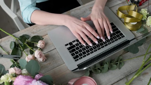 Office workplace essentials: laptop, paper notebook, bouquet of flowers on the rustic wooden table background, florist workplace, Flower business woman.