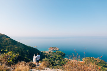 Fototapeta na wymiar Newlyweds on the mountain in Montenegro, overlooking the island of Sveti Stefan. Wedding in Montenegro.