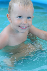 Fototapeta na wymiar little baby boy in the water pool. Cute blue-eyed boy in the water basin. Child learning to swim. Child Safety