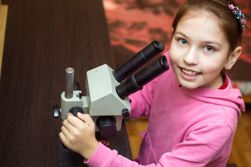 A little girl at home conducting research with a microscope