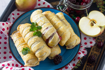 Breakfast background. Homemade apple mini strudel with fresh apples, cherries, blackberries and powdered sugar.