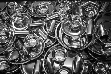 Amount of clean dishes with many grey stainless steel plates glasses bowls spoons and cutlery 