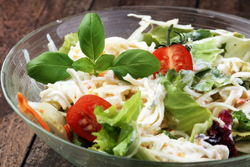 bowl of salad with vegetables and greens on wooden table