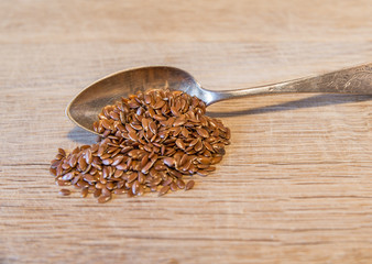 Ein Silberlöfel mit Leinsamen auf einem Holzbrett