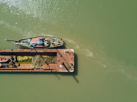 View from above bird eye of abandoned damaged rusted boats and barge in a harbor with green sea a sunny day Isle of Sheppey England United-Kingdom