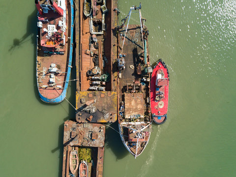 View from above bird eye of abandoned damaged rusted boats and barge in a harbor with green sea a sunny day Isle of Sheppey England United-Kingdom