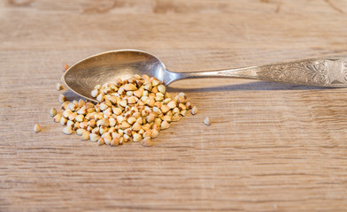 Ein Silberlöfel mit Buchweizen auf einem Holzbrett