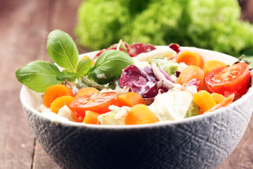 bowl of salad with vegetables and greens on wooden table