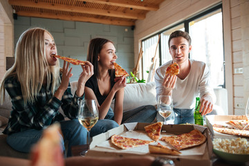 Three friends eating pizza in house