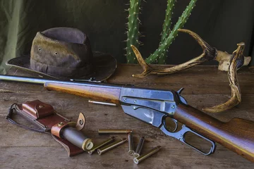 Fototapeten westliches Stillleben. Amerikanischer Jagdkarabiner und Jagdmunition auf altem Holztisch © stsvirkun