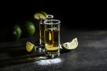 Tequila shots with lime slices and salt on table