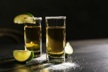 Tequila shots with lime slices and salt on table