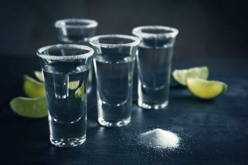 Tequila shots with lime slices and salt on table