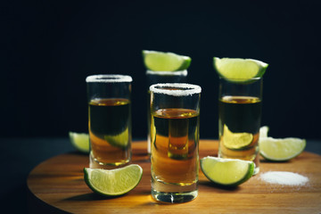 Tequila shots with lime slices and salt on table