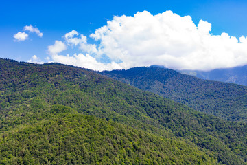 Fototapeta premium Mountains and clouds in a bright blue sky.