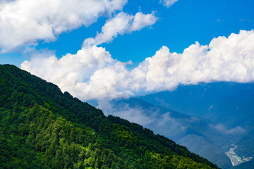 The slope of the wooded mountain, the blue sky and the city at the foot.