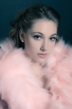 Sensual retro 1940s glamour portrait of young woman wearing feather boa.