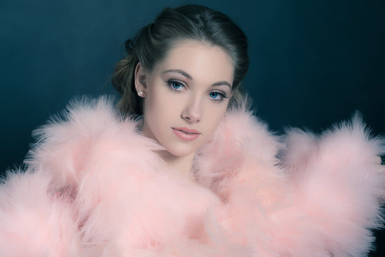 Sensual retro 1940s glamour portrait of young woman wearing feather boa.