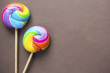 two rainbow color lollipops on brown background