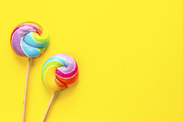 two rainbow color lollipops on yellow background