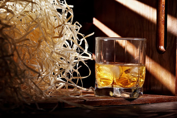 Glass of whiskey and ice.In wooden container for transporting with wooden chips. Horizontal shot