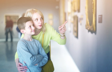 Mother and son looking at paintings in halls of museum