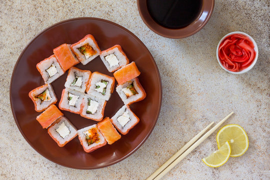 Sushi set on a stone background - roll Philadelphia classic, roll Cheese salmon and roll Jamaica with pickled ginger and soy sauce. Copy space.