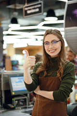 Happy cashier woman on workspace showing thumbs up.