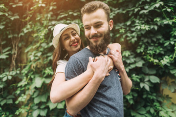 Fototapeta premium Young and stylish couple walking on the street of summer. Bearded boy and fashionable girl are loving and flirting.