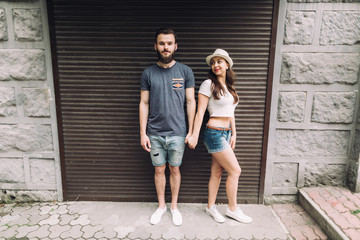 Obraz na płótnie Canvas Young and stylish couple walking on the street of summer. Bearded boy and fashionable girl are loving and flirting.