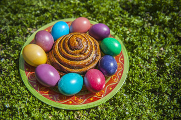 Plate of colorful Easter eggs on a green grass background