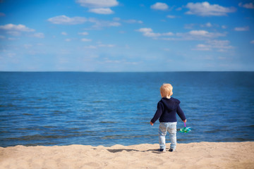 1 year little boy stand on the beach and looking on the sea