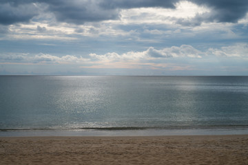 View from sandy beach on dramatic tropical cloudy sky and sea