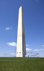 Obraz premium The Washington Monument surrounded by flags against blue sky. Vertical.