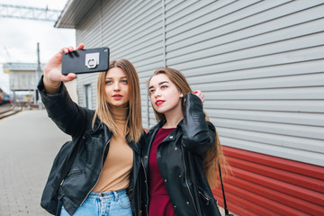 Two young girls taking selfie using smartphone