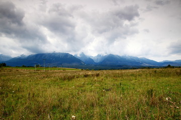 Eastern part of High Tatra mountains in low level clouds (Slavkovsky peak, Prostredny hreben, Lomnicky peak) in a rainy autumn day, from a grassy field in Nova Lesna (Tatra National Park, Slovakia).