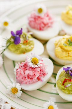 Deviled eggs with various fillings decorated with fresh herbs and edible flowers
