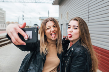 Fototapeta premium Two young girls taking selfie using smartphone