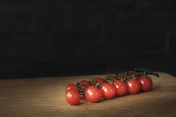 tomatoes branch on rustic table over dark background, healthy food