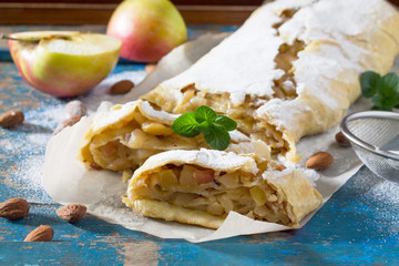 Freshly baked apple strudel with almonds, decorated with powdered sugar and mint leaves.