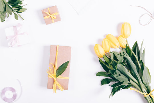 Yellow tulips and gift box lying on white background