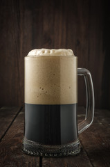 Dark beer mug with foam on dark background