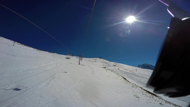 View from top to bottom on snow-covered ski slope, traces, skier and paraplane from the chair lift. First-person view