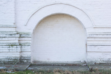 The walled-up door with stone arch in an ancient white plastered wall background, photo frame