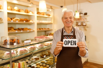 Happy senior man opening his own bakery