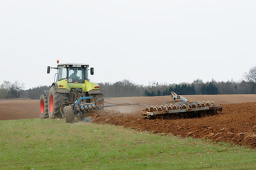 Rolnik uprawiający ziemię traktorem na polu. 